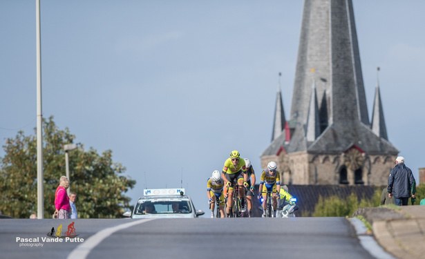Renners rijden op Kachtem af, met de kerktoren op de achtergrond